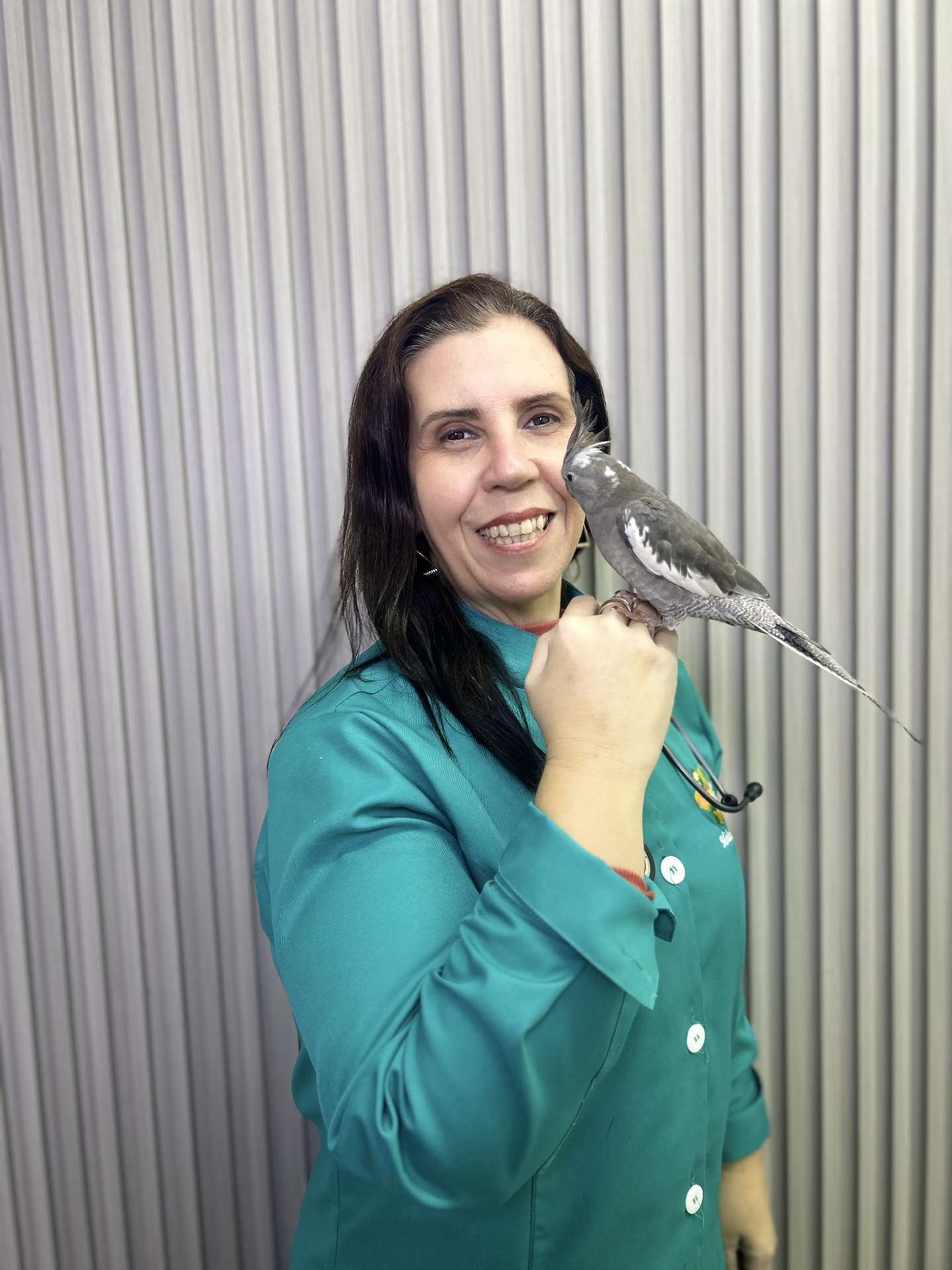 Dra. Ana Victória Rigon sorrindo com sua calopsita no ombro